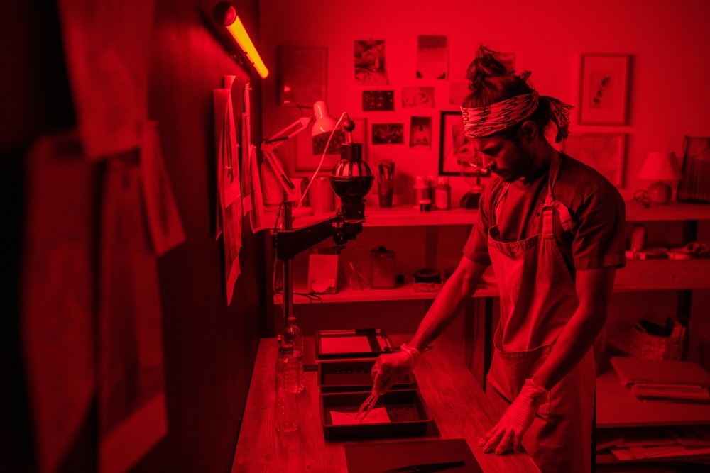 一名年轻人在暗室中使用钳子的场景。 传统的照相冲印工艺以彩色插图呈现。