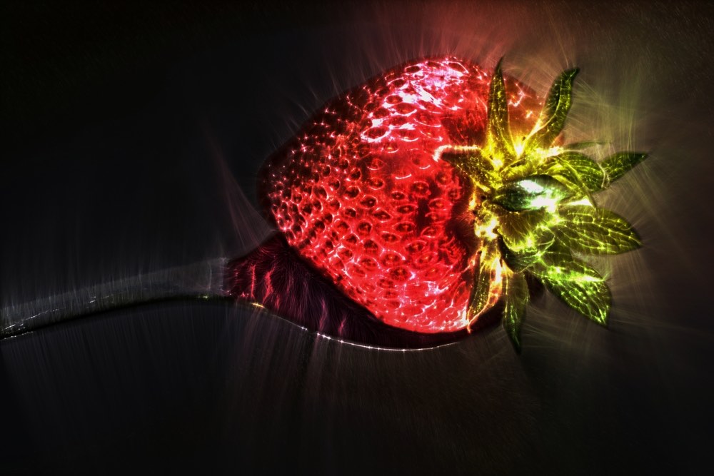 一张克里安照片，上面是放在勺子上的草莓。 彩色克里安摄影。